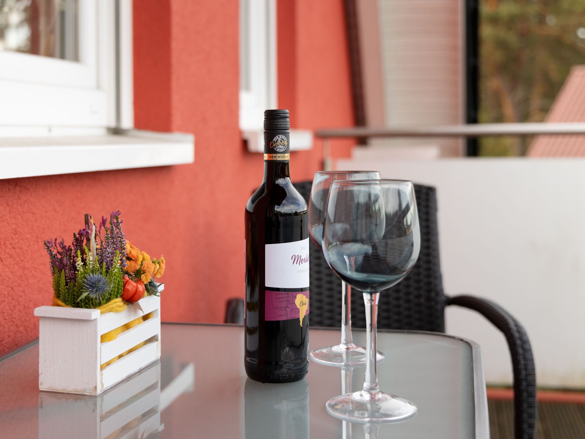 A bottle of wine and an empty glass on a table with a decorative plant.
