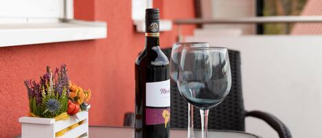A bottle of wine and an empty glass on a table with a decorative plant.