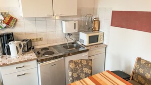 A compact kitchen with a refrigerator, microwave, toaster, kettle, and sink. - Schmidt (App. 3) by Interhome (Zinnowitz)