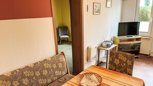 A living room with a sofa, a table with a basket, a TV, and a chair. - Schmidt (App. 3) by Interhome (Zinnowitz)