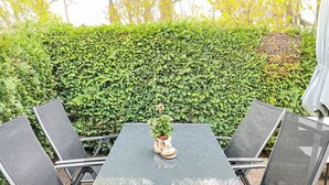 A patio with a table and chairs, a potted plant, and a hedge in the background. - Schmidt (App. 3) by Interhome (Zinnowitz)