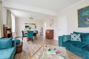 A modern living room with a sofa, coffee table, and a dining area with chairs and a table.