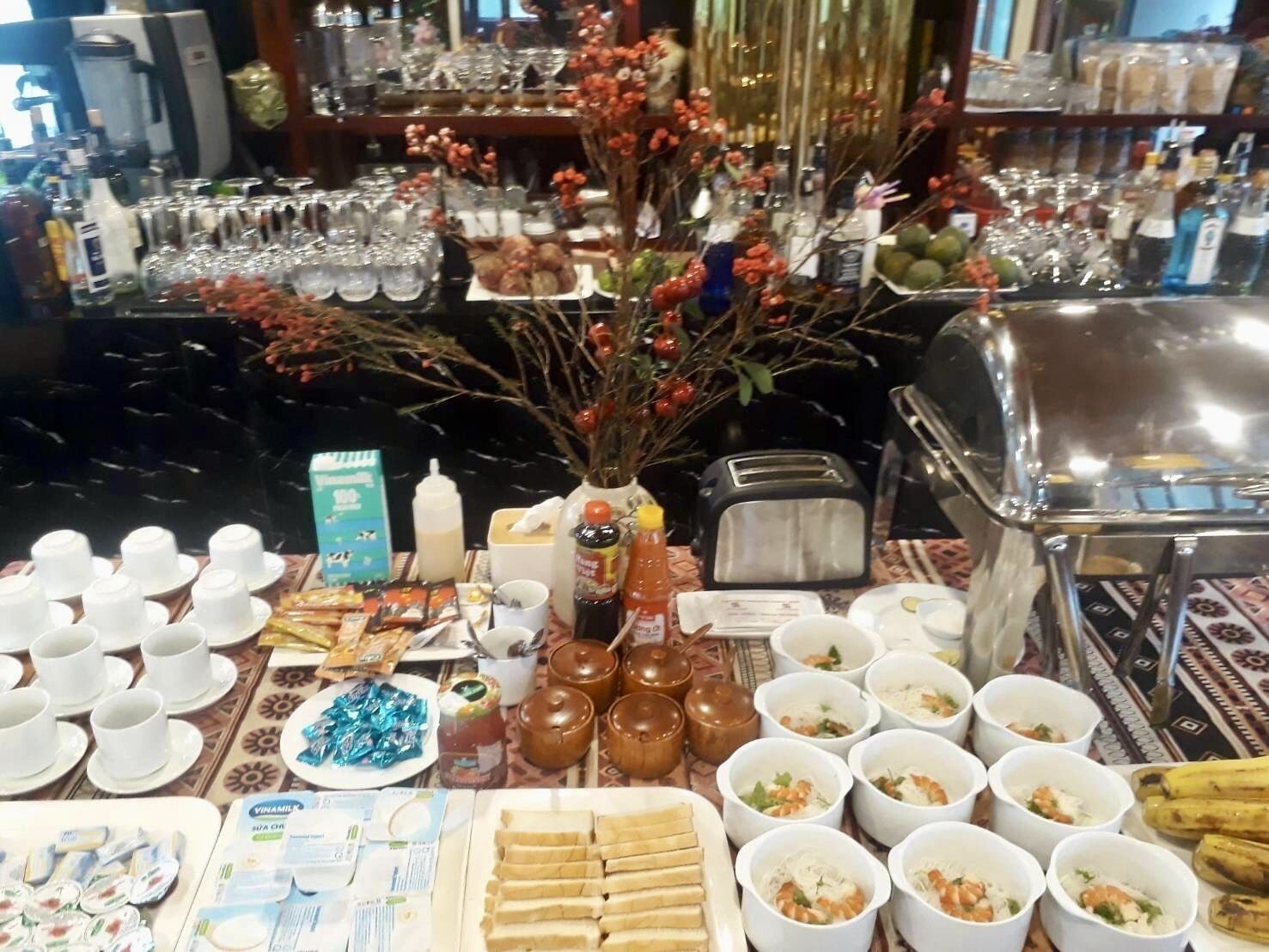 Una mesa de buffet con diferentes alimentos, incluyendo tazones de sopa, bandejas de pan y una variedad de salsas.