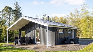 Une cabane moderne dotée d’un patio couvert, d’une cheminée et d’une terrasse.