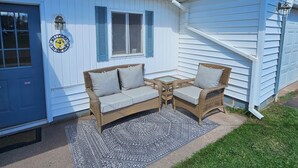A white house with a blue door, a wicker sofa set, and a patterned rug. - Becky's Bee Hive, Clean, Cozy, Affordable and Family Friendly! (Ironwood)