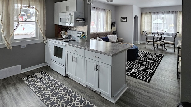 A modern kitchen with white cabinets, a central island, and pendant lighting. - Becky's Bee Hive, Clean, Cozy, Affordable and Family Friendly! (Ironwood)
