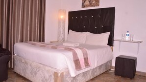 A neatly made bed with a striped blanket, a bedside table with a water bottle, and a picture on the wall. - Napier  Family-sized condo in Central Bulawayo (Bulawayo)