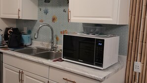 A kitchen with white cabinets, a microwave, a sink, and a bamboo curtain. - Napier  Family-sized condo in Central Bulawayo (Bulawayo)