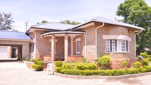 A two-story house with a stone facade, a covered porch, and a small garden. - Napier  Family-sized condo in Central Bulawayo (Bulawayo)