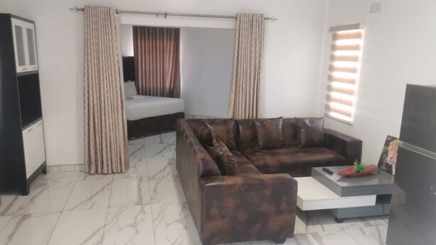 A modern living room with a sofa, a small table, a TV, and a refrigerator. - Napier  Family-sized condo in Central Bulawayo (Bulawayo)