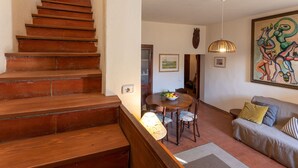 Una scala conduce a una zona pranzo con un tavolo apparecchiato per due, un divano e un quadro appeso al muro.