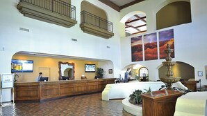 A spacious lobby with a reception desk, large windows, and a fountain.