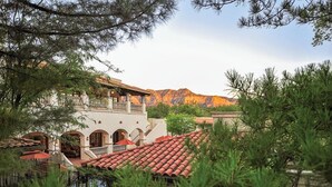 A building with a red-tiled roof, multiple balconies, and a mountainous backdrop.