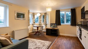 A compact living space with a dining area, kitchen, and a large window with curtains.