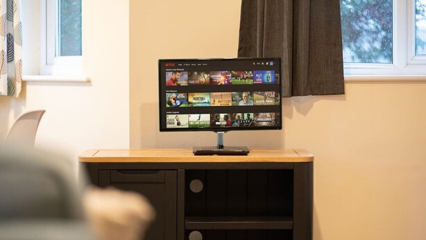 A television mounted on a wooden cabinet with a remote control on top.
