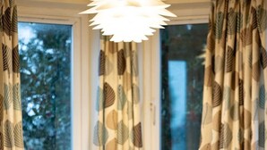 A dining area with a round table, two white chairs, and patterned curtains.