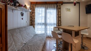 Una habitación acogedora con sofá, una mesa de madera y dos taburetes de bar.