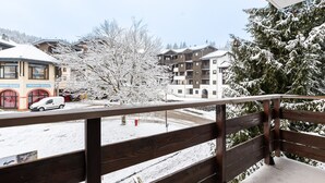 Un balcón de madera con vistas a una calle nevada y edificios.