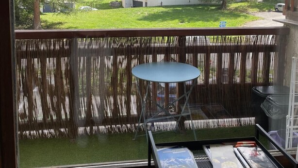 Ein Balkon mit Tisch, Blick auf einen Berg und ein Gebäude im Hintergrund.