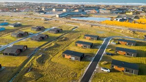 Vista aérea de uma área residencial com casas modernas, uma estrada e um corpo d'água.