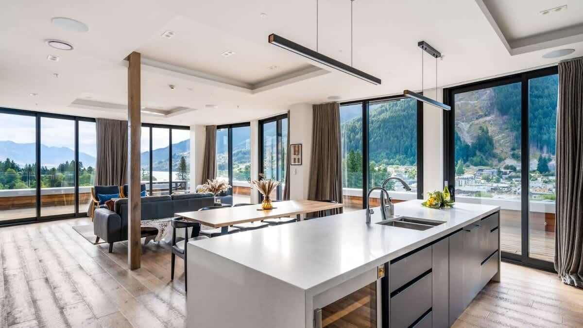 Une cuisine moderne dotée d’un grand îlot central, d’un coin repas et de grandes fenêtres offrant une vue sur les montagnes.