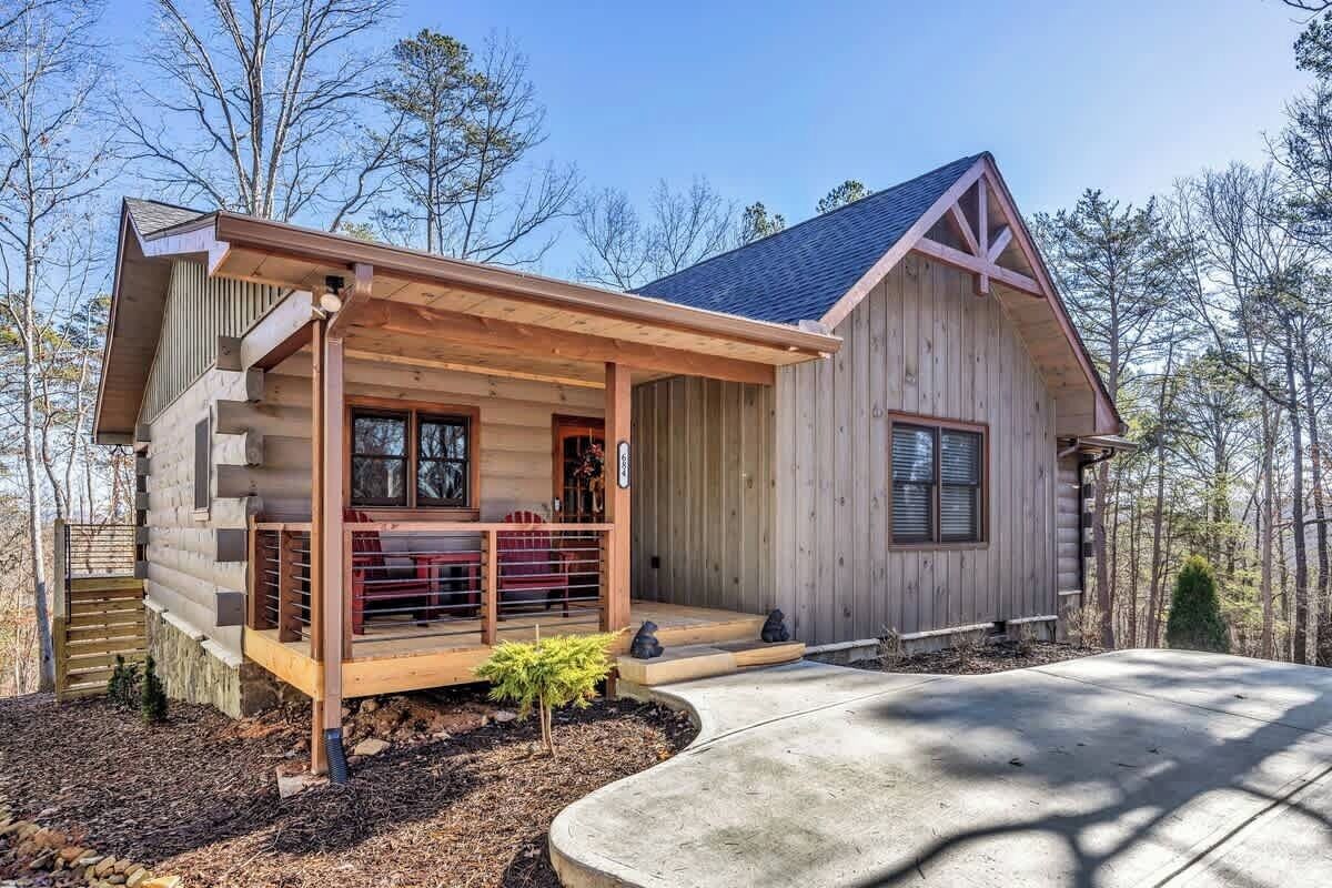 Eine Blockhütte mit Veranda, überdachter Eingangspartei und kleinem Vorgarten.