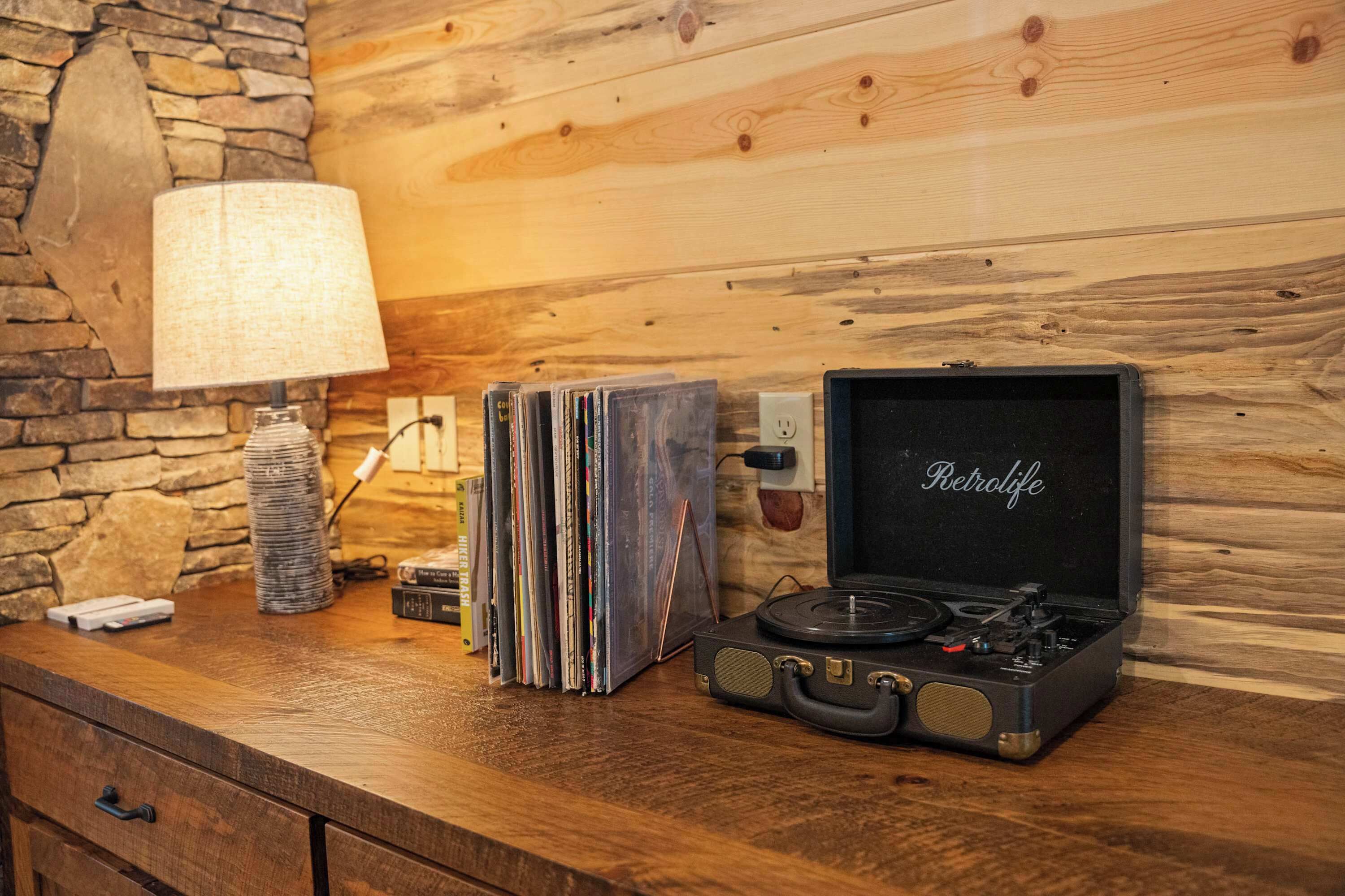 Une table en bois, une lampe, une pile de CD et un vieux tourne-disque.