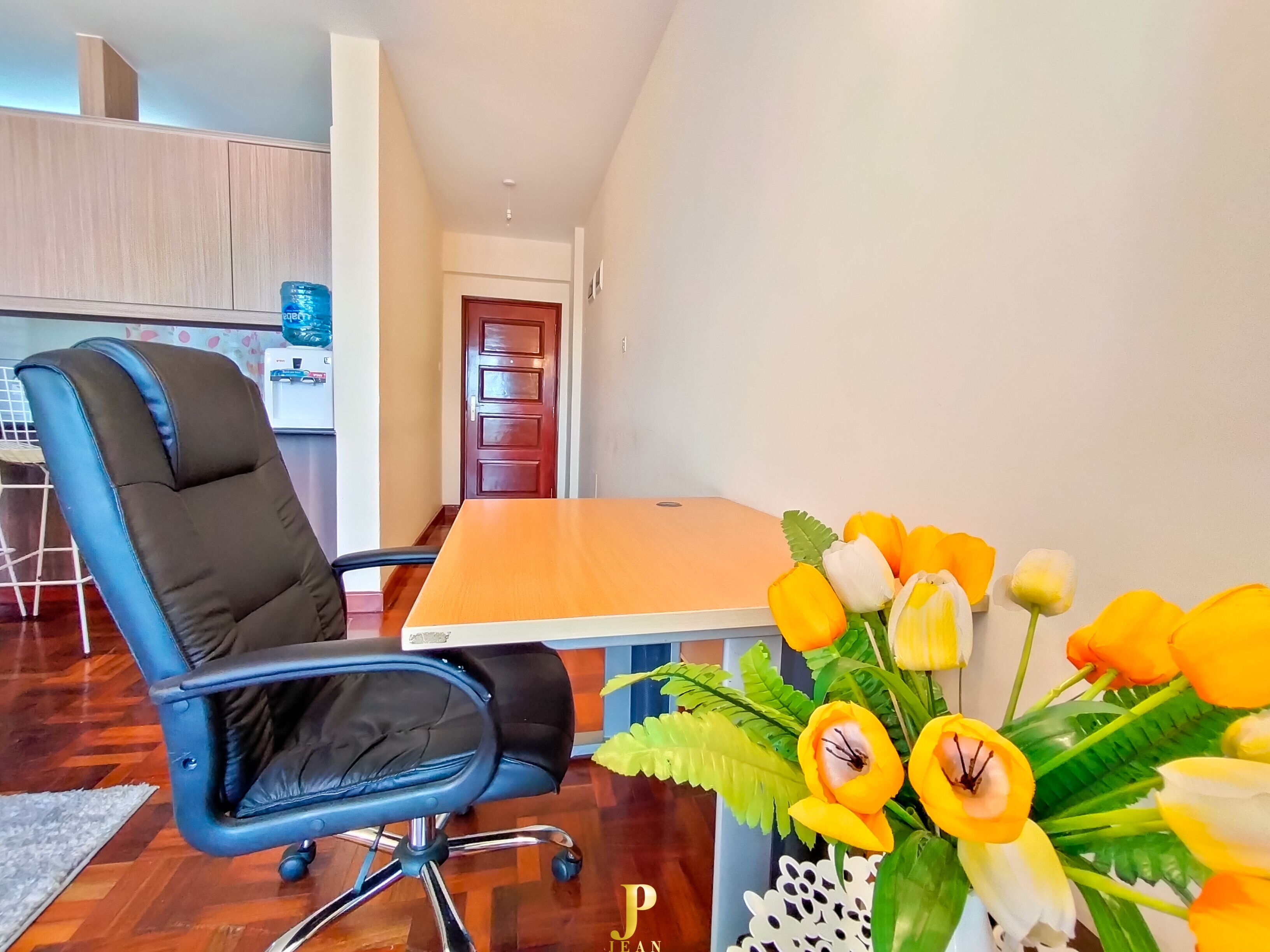 Un espace de bureau moderne avec un fauteuil de bureau bleu, une table en bois et un vase rempli de fleurs jaunes.