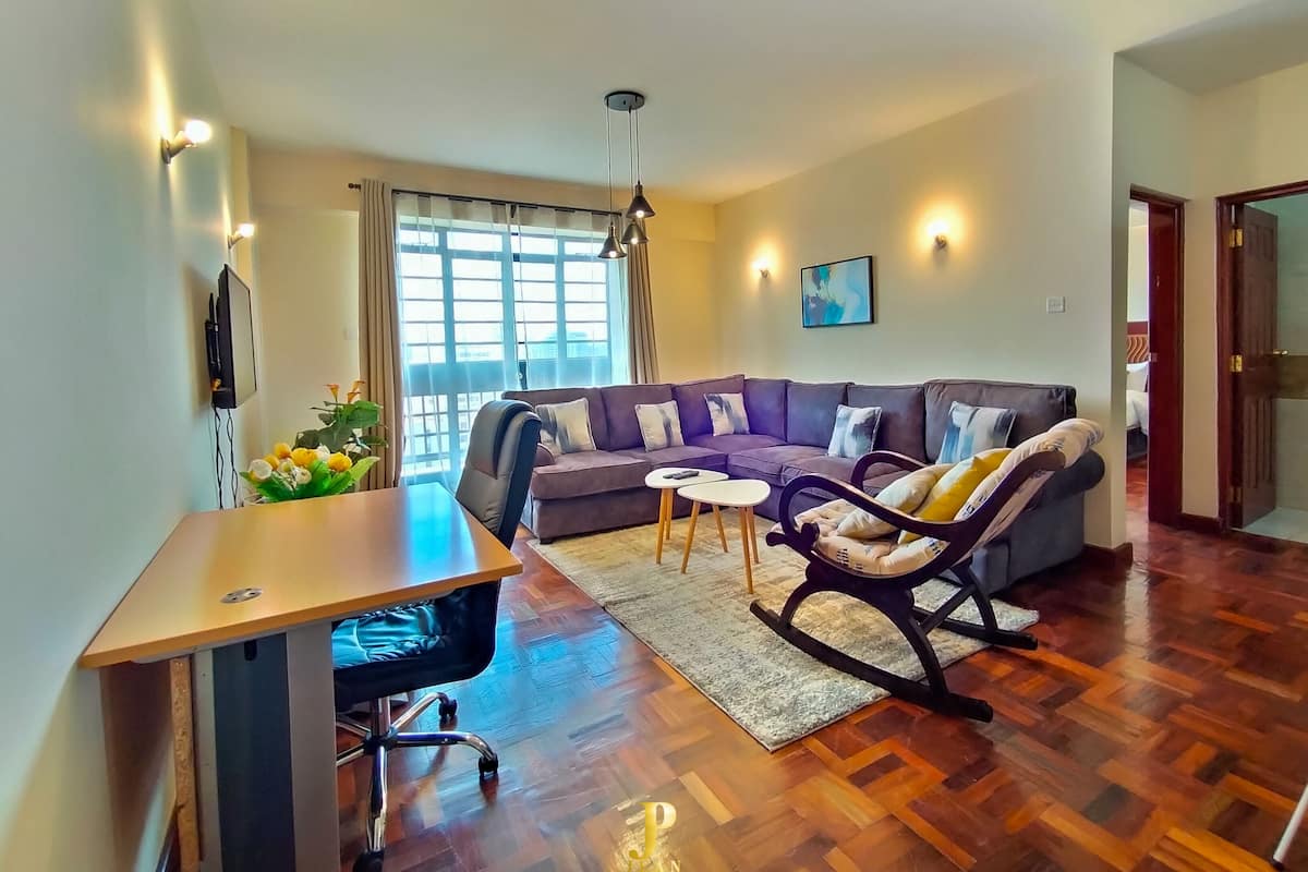 Een moderne woonkamer met een modulaire bank, een eettafel en een schommelstoel.