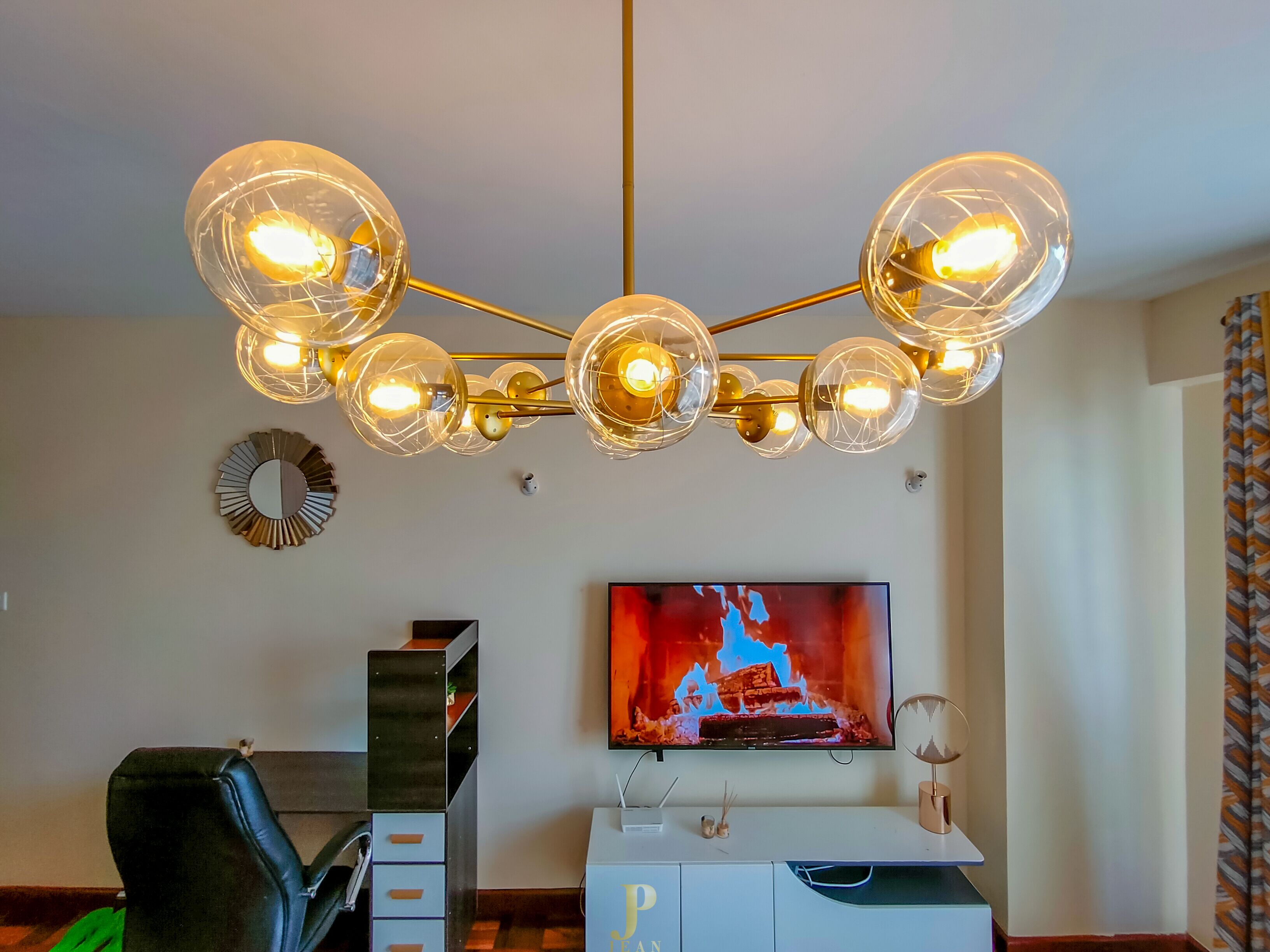 Ein modernes Wohnzimmer mit einer Kristallleuchter, einem Flachbildfernseher und einer weißen Unterhaltungseinheit.