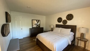 A bedroom with a bed, bedside tables, a dresser, a bench, and decorative wall art. - Modesto 2 Bdrm/2 Ba unit in gated area nr shopping, eateries, in unit wash/dryer (Modesto)