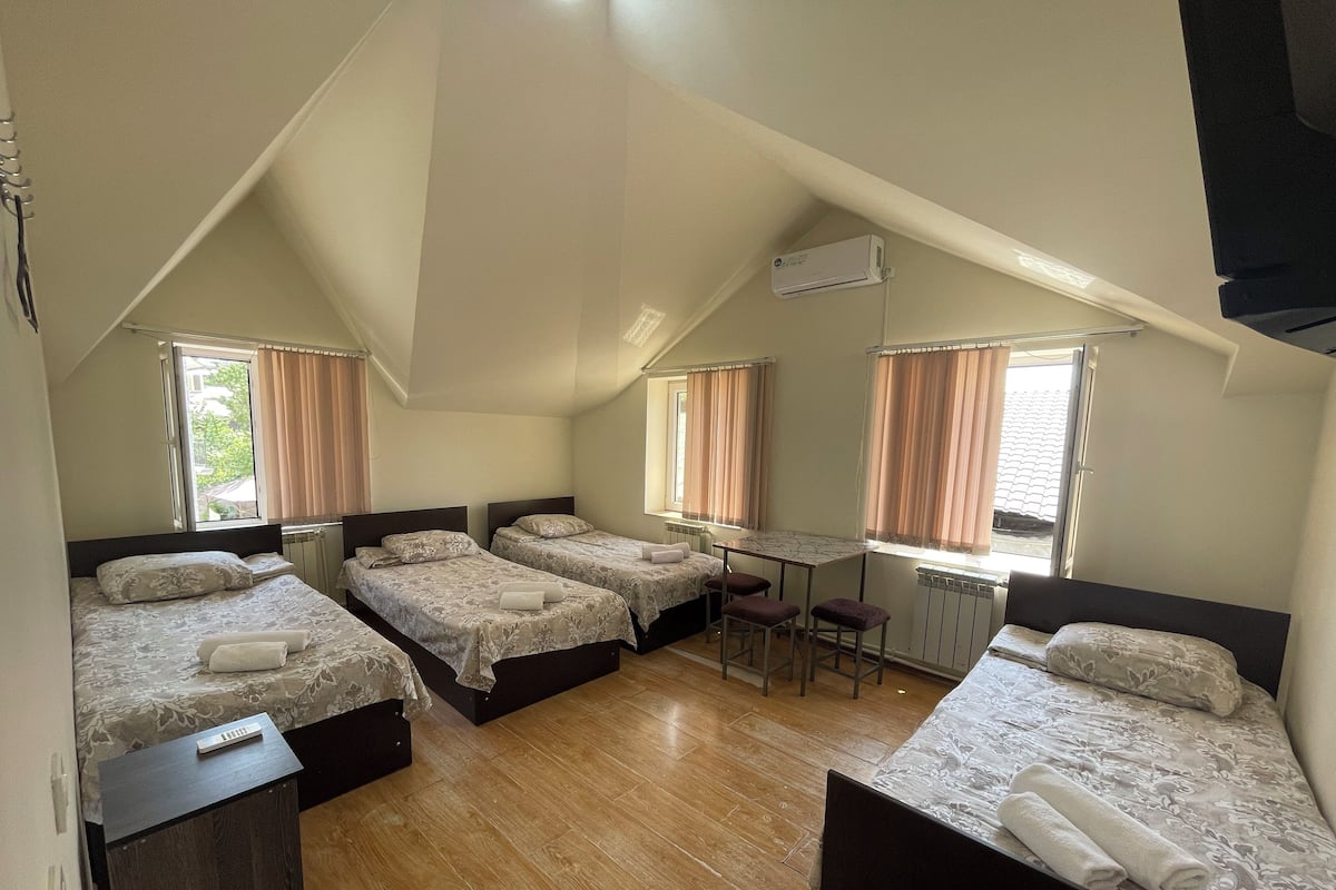 Une chambre de dortoir avec quatre lits, une petite table et une fenêtre.