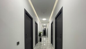 A modern hallway with marble flooring, dark doors, and recessed lighting. - Noragyugh Guesthouse (Yerevan)