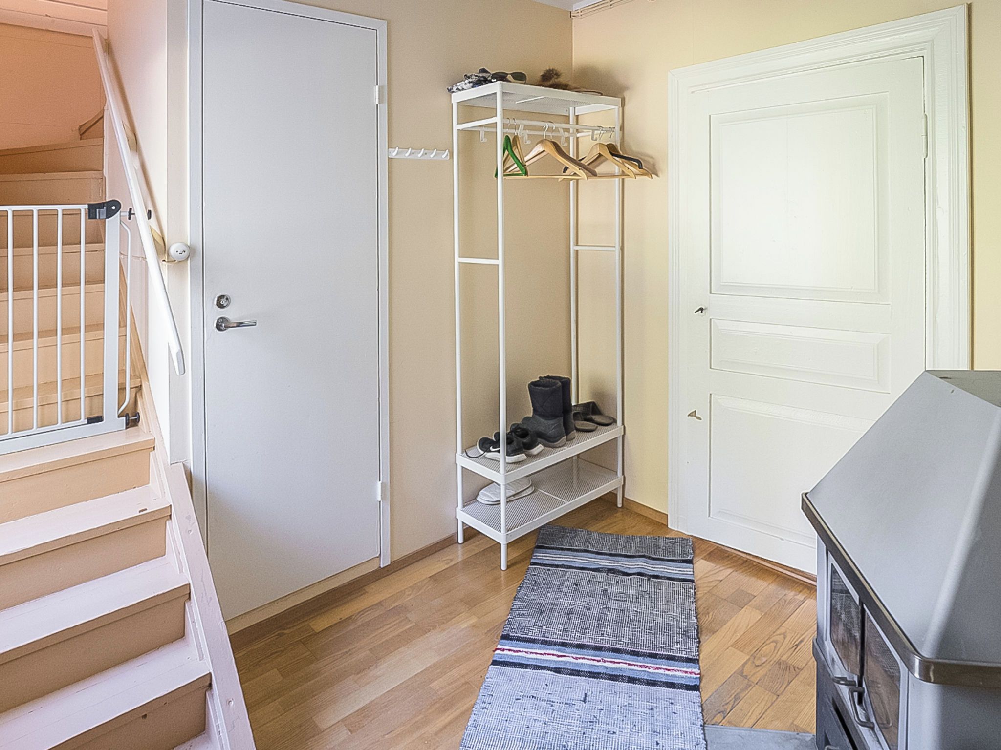 Un couloir avec un meuble à chaussures, une porte et un escalier.