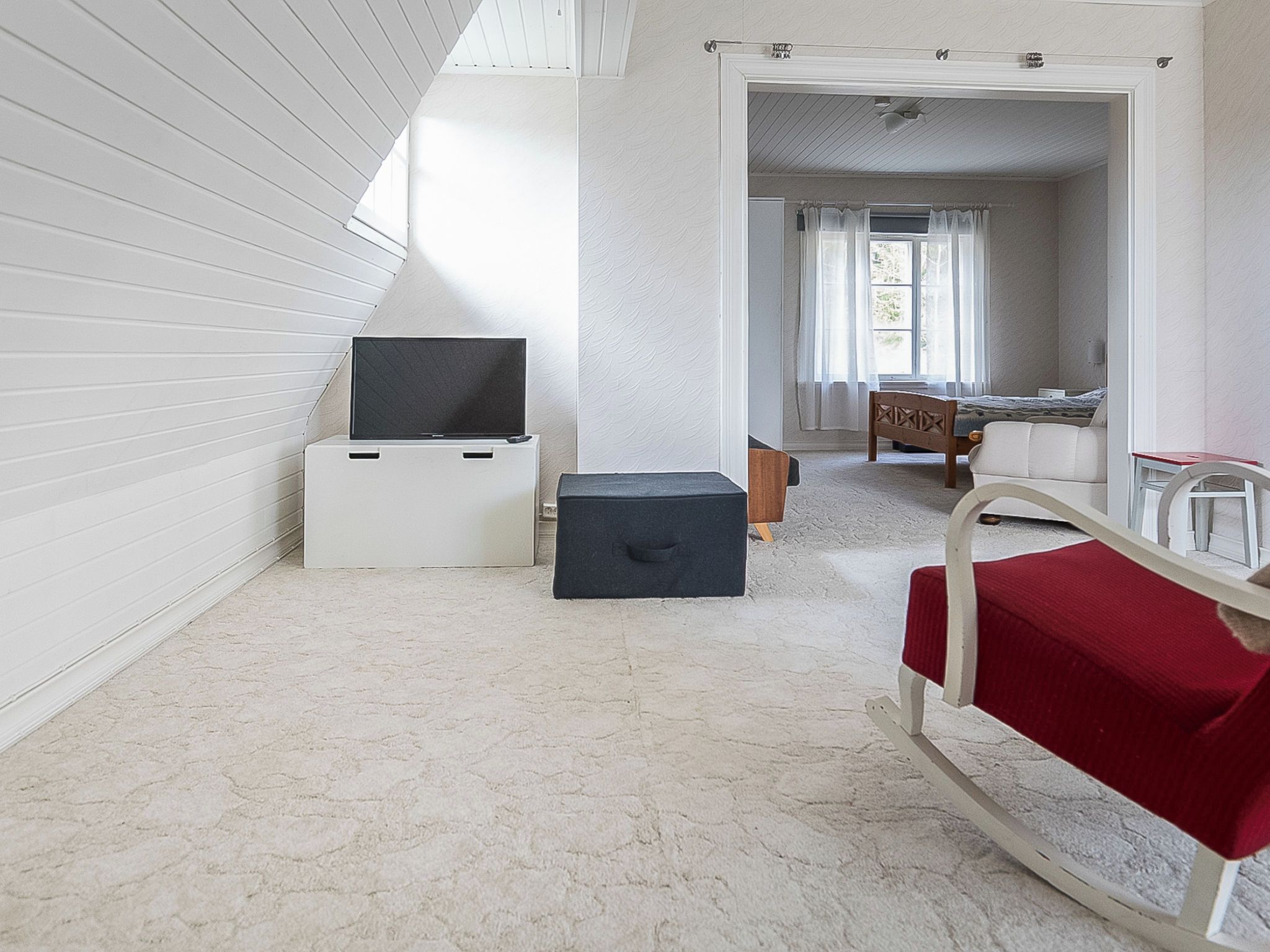 A room with a bed, a small table, a television, and a storage box.