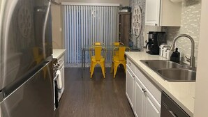 Una cucina moderna con elettrodomestici in acciaio inossidabile, un lavello doppio e sedie gialle.