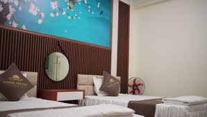 A hotel room with two beds, a wooden headboard, a wall-mounted mirror, a red fan, and a floral mural. - Sunrise Ninh Binh Hotel (Hoa Lu)