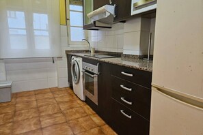 A kitchen with a washing machine, oven, and a sink.