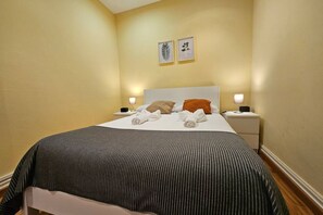 Ein Hotelzimmer mit einem Bett, zwei Nachttischen, einem Kopfteil und zwei Wandbildern.