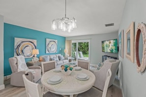 A modern living room with a round dining table, sofas, and artwork on the walls.