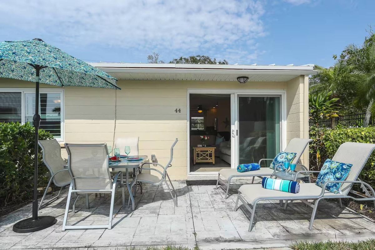 A two-story building with a patio area featuring outdoor furniture and a large umbrella.