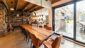 Un comedor espacioso con una mesa y sillas de madera, una pared de piedra y vistas al patio exterior.