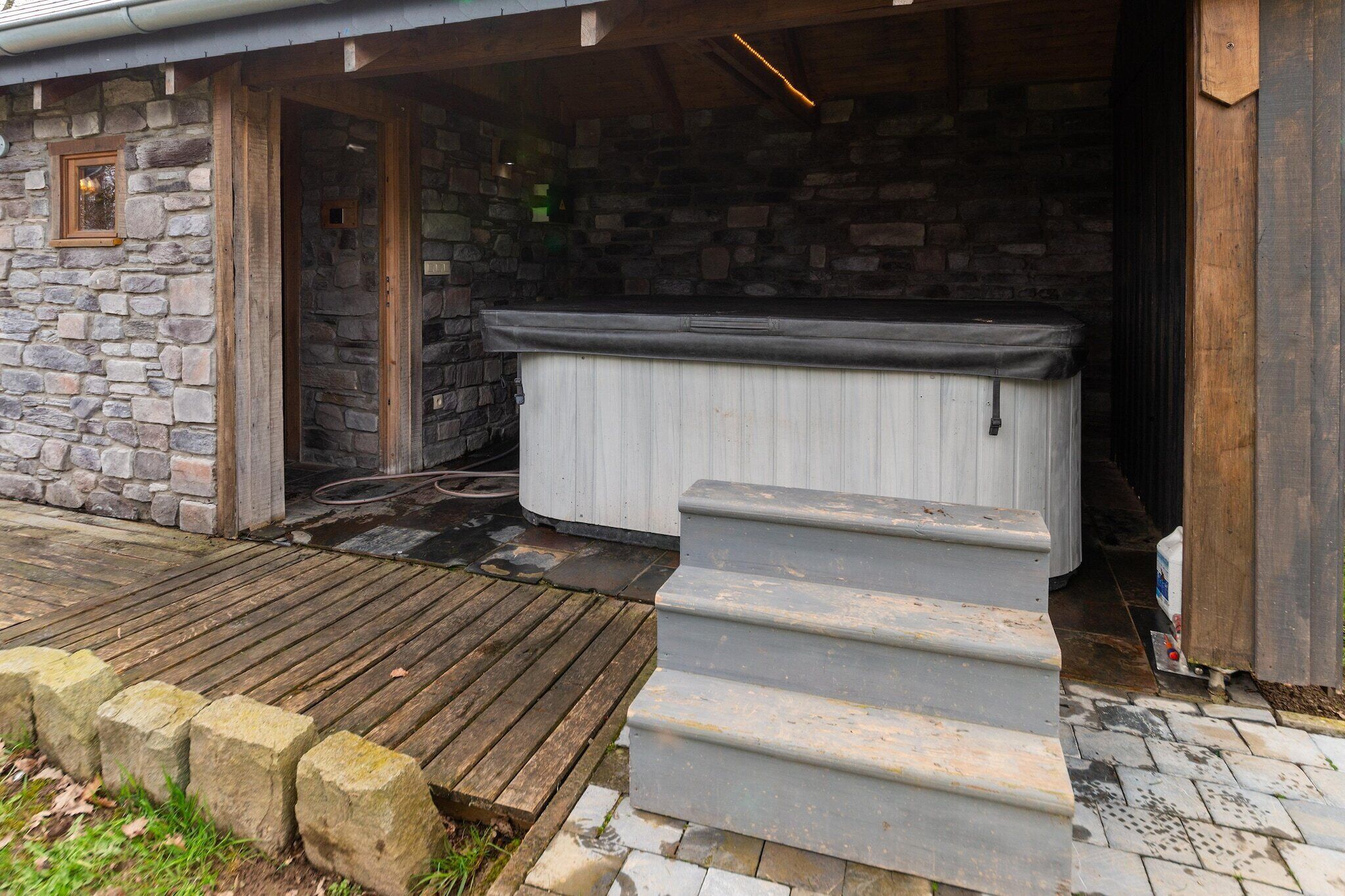 Un edificio de piedra con una terraza de madera y un jacuzzi.