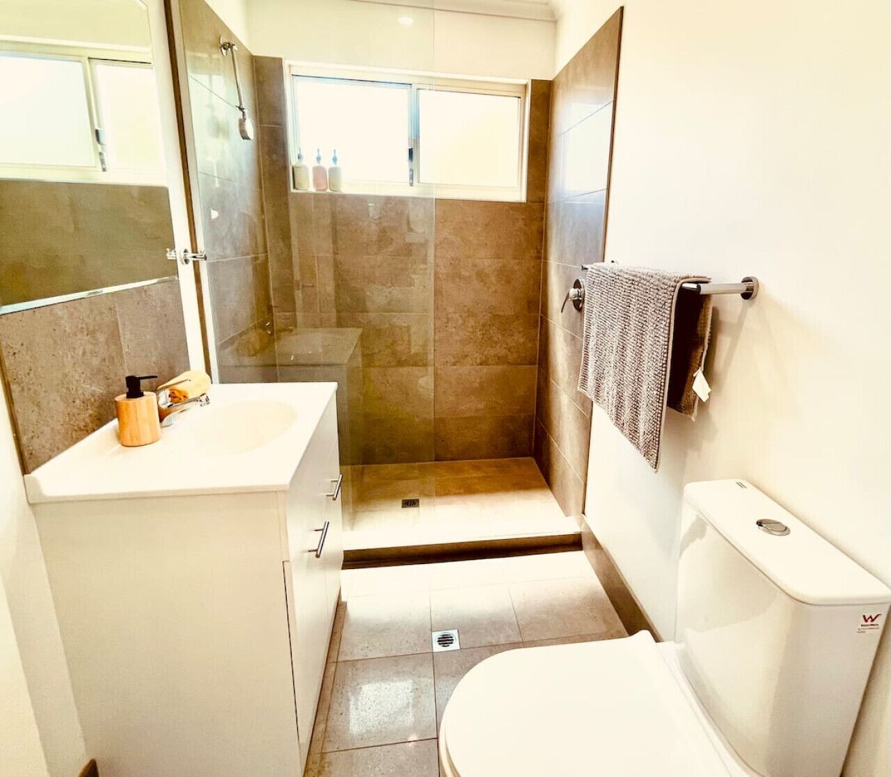 Ein Badezimmer mit Dusche, Toilette, Waschbecken und Handtuchhalter.