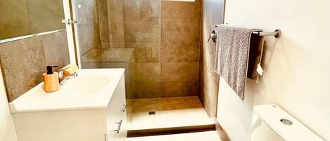 Ein Badezimmer mit Dusche, Toilette, Waschbecken und Handtuchhalter.