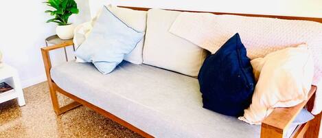 Un canapé avec un coussin gris clair, un oreiller bleu foncé et un oreiller blanc.