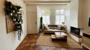 A living room with a sofa, coffee table, and TV. There are plants on a wall-mounted board and a fireplace. - Beautiful and cozy monumental house in the city center. (Amersfoort)