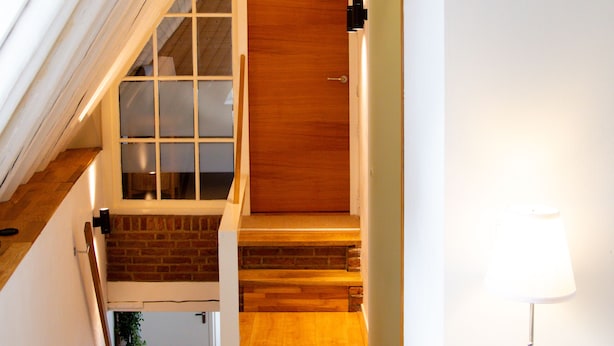 A staircase leading to a wooden door, a white radiator, and a lamp on a bedside table. - Beautiful and cozy monumental house in the city center. (Amersfoort)