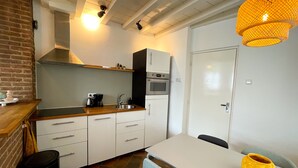A compact kitchen with a sink, stove, and a dining area with a table and chairs. - Beautiful and cozy monumental house in the city center. (Amersfoort)