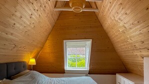 A bedroom with a sloped ceiling, a bed, a window, and a lamp. - Beautiful and cozy monumental house in the city center. (Amersfoort)
